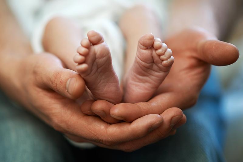 Dad holds in his hands a small baby foots